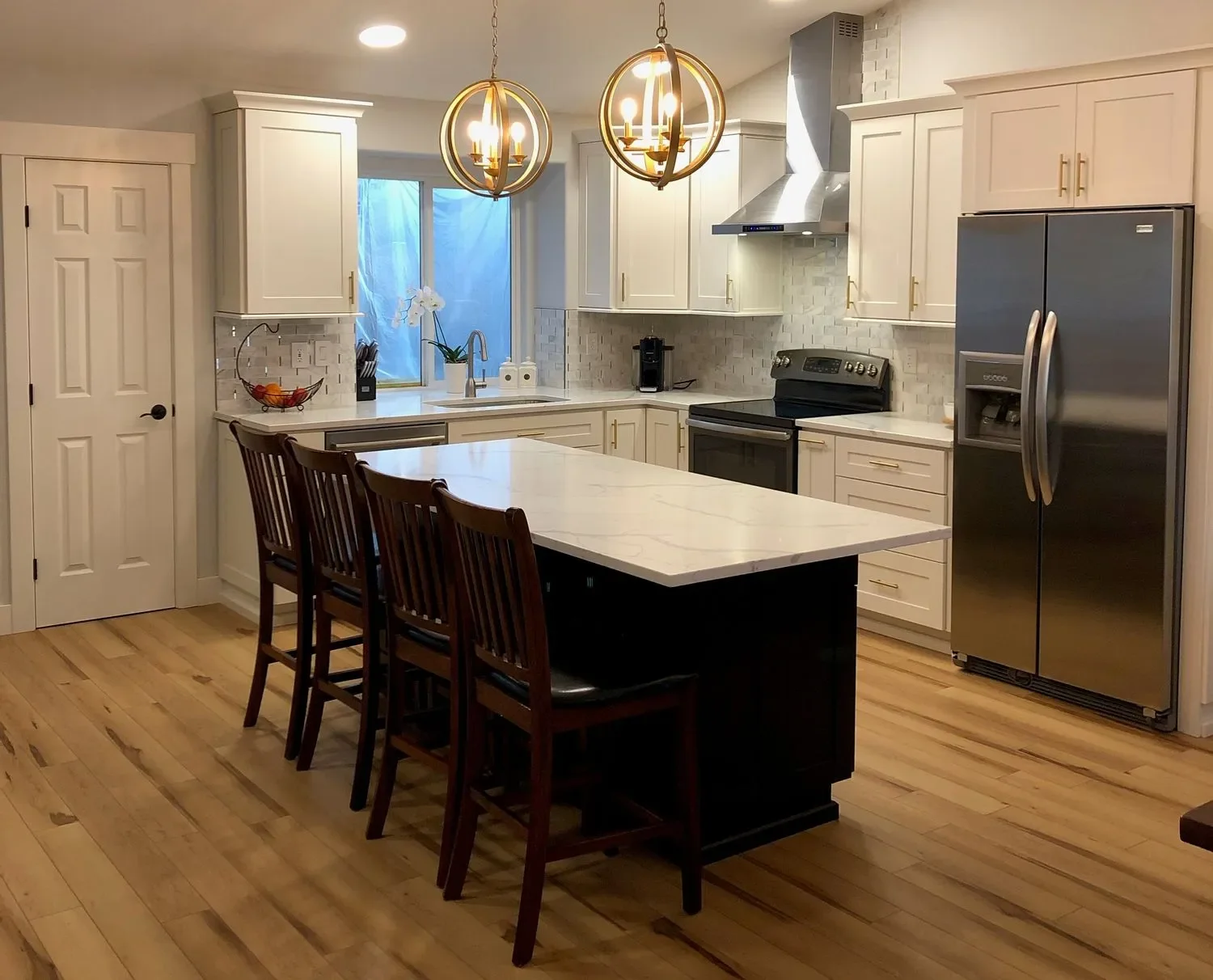 Cream cabinetry with black island, white quartz counters, subway tile backsplash, and stainless steel appliances