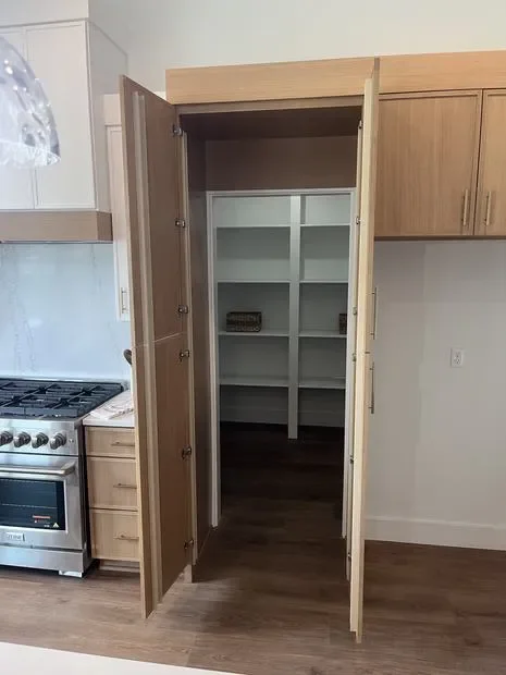 Natural wood pantry cabinet with glass doors and interior shelves in kitchen