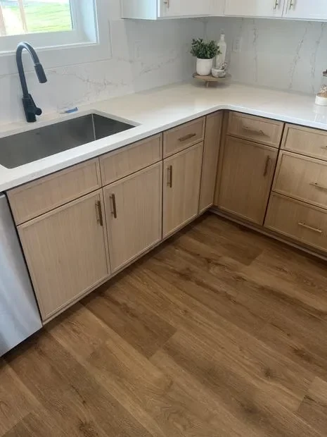 Light wood kitchen cabinets with white quartz countertops and black undermount sink