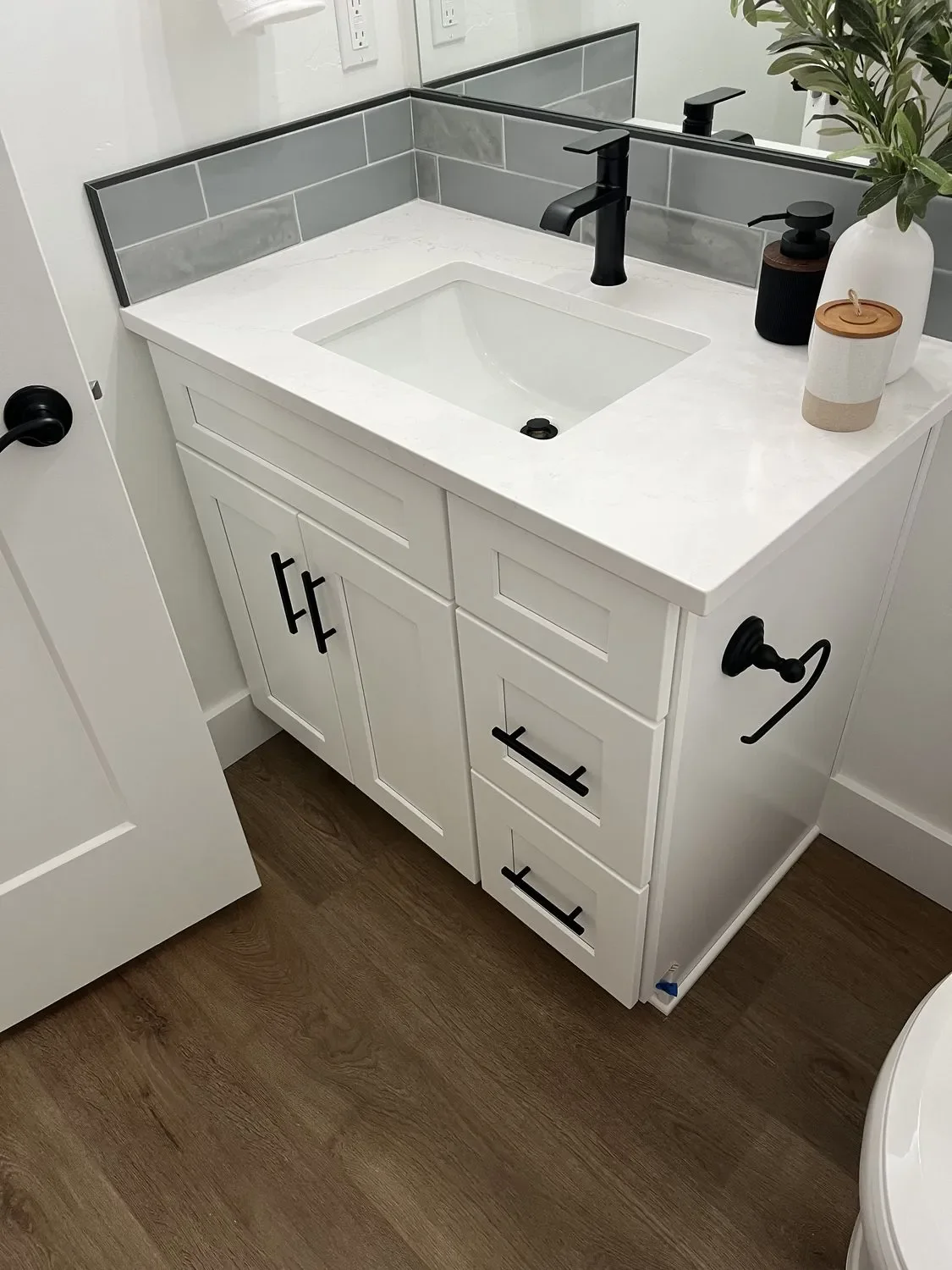 White shaker vanity with quartz countertop, integrated sink, and gray subway tile backsplash