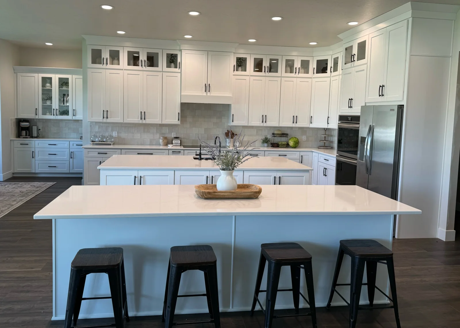 White shaker kitchen cabinets with glass doors, large island, and stainless steel appliances