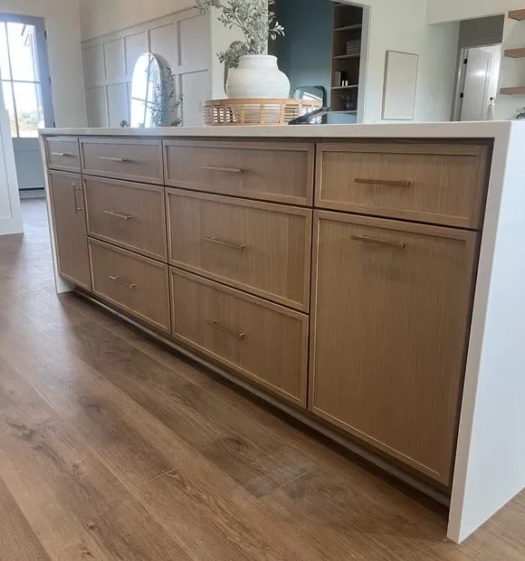 Stained wood kitchen island with nine drawers, cabinet doors, and white quartz countertop