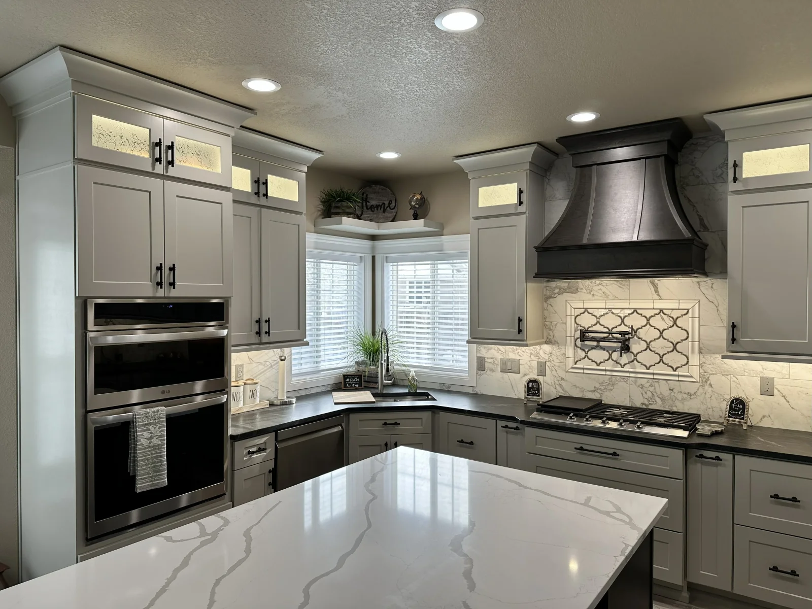Gray shaker cabinets with stainless steel appliances and marble countertops in modern kitchen