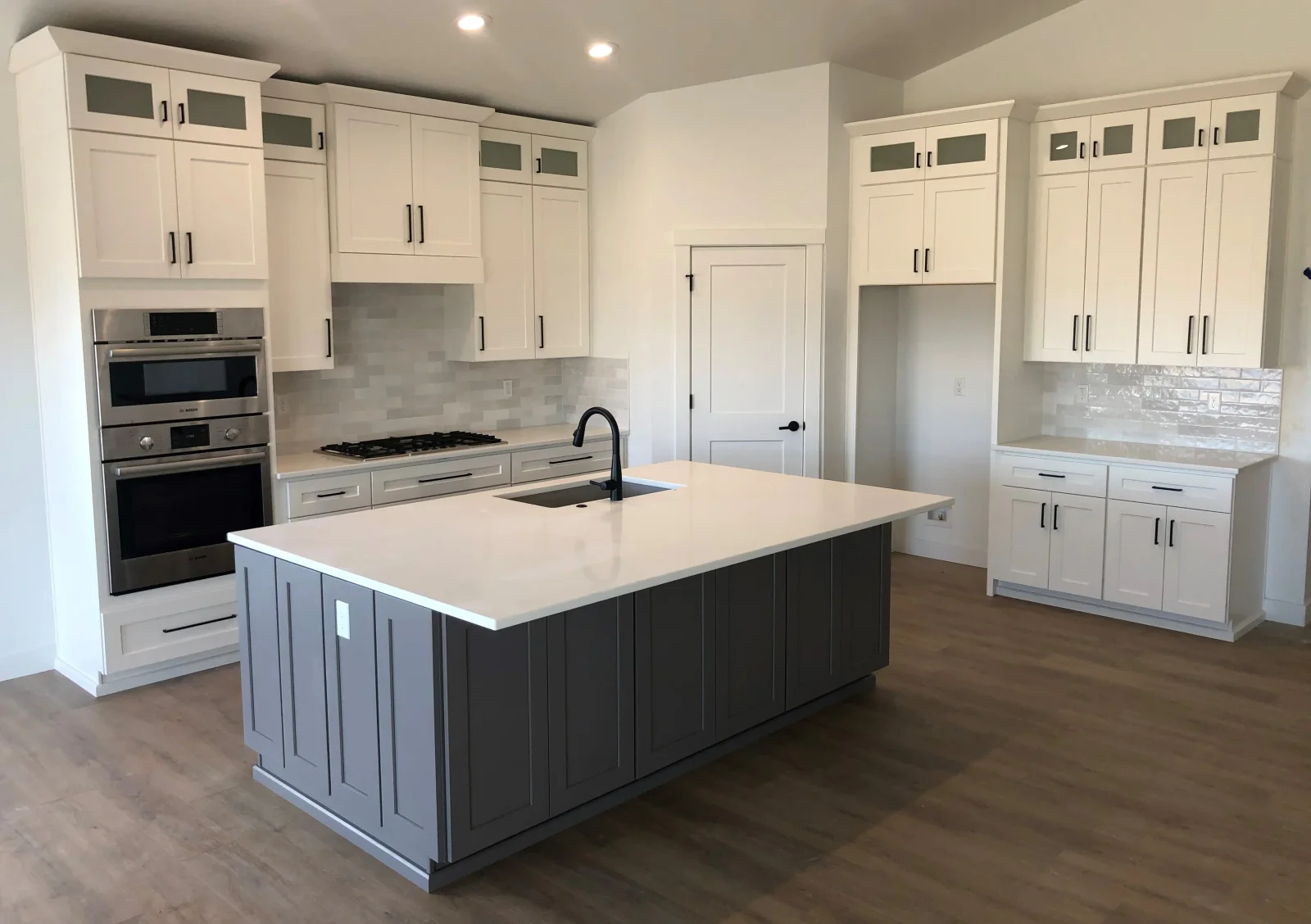White shaker cabinets with grey island, quartz countertop, and stainless steel appliances